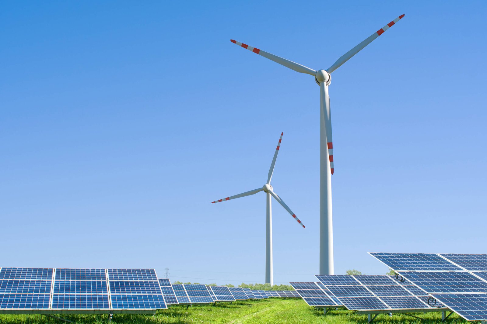 solar panels and wind turbines generating electricity at green energy renewable power plant with blue sky background